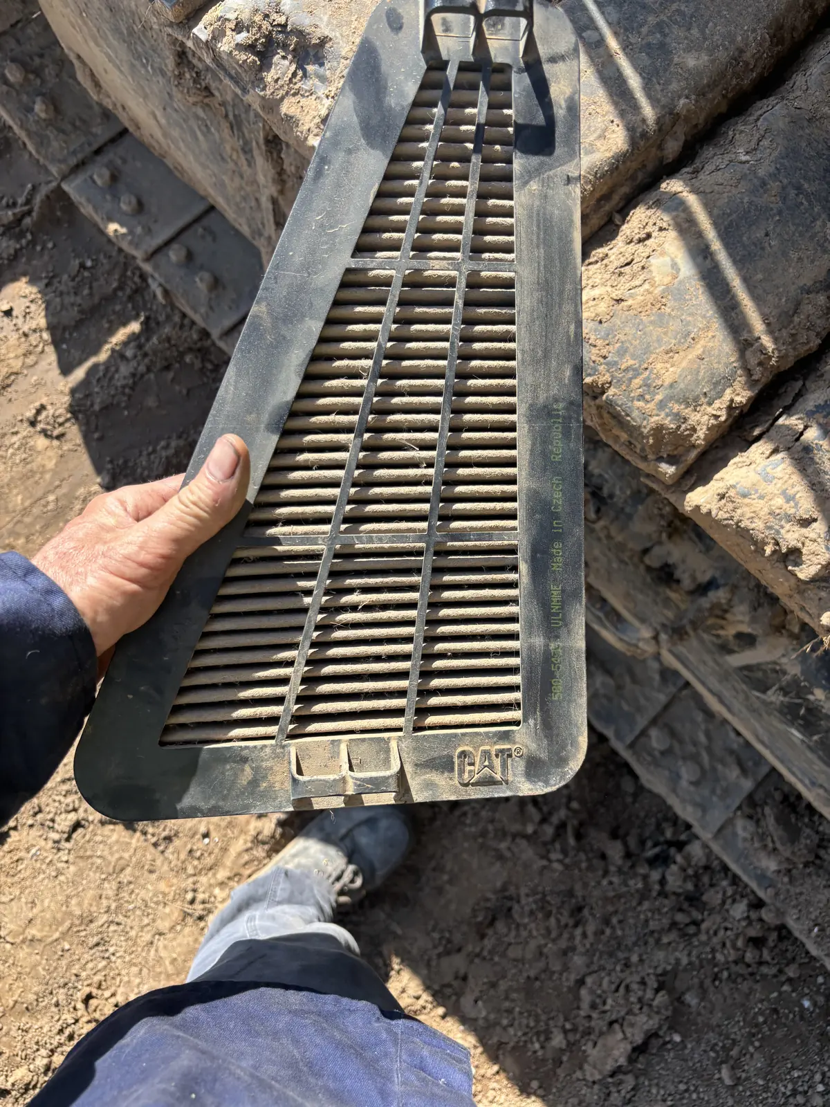 Technician cleaning a CAT radiator screen during maintenance