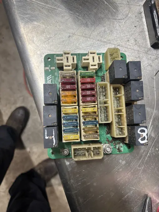 Technician diagnosing a relay and fuse board