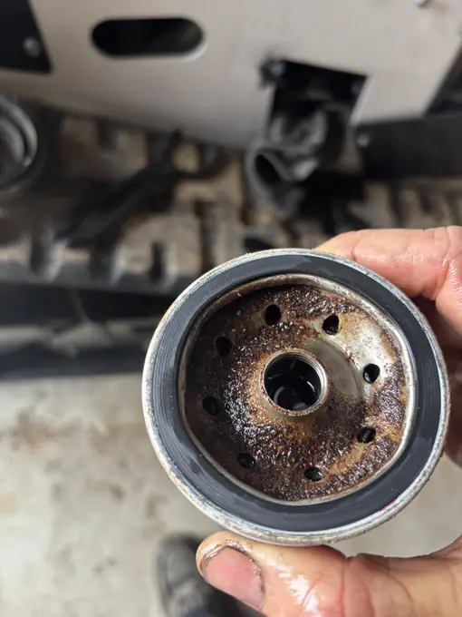 Technician holding a spent oil filter during diesel preventive maintenance