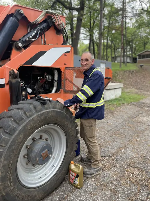 Certified technician repairing a boom lift engine in the field