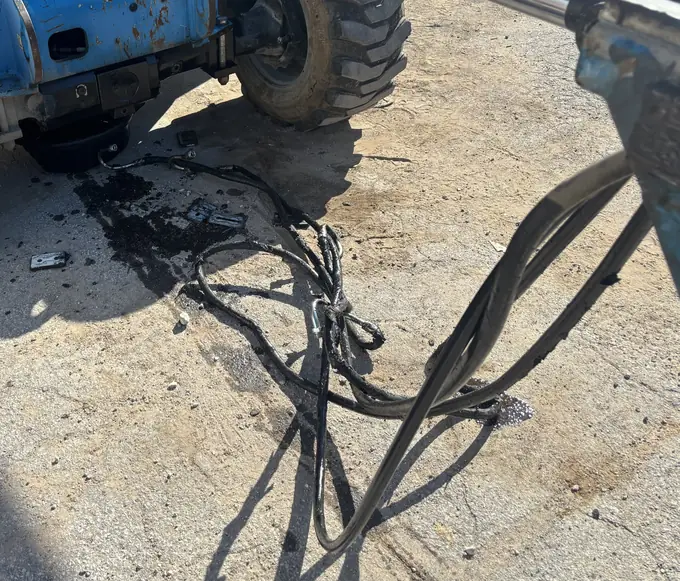 Technician repairing a damaged wiring harness on heavy equipment